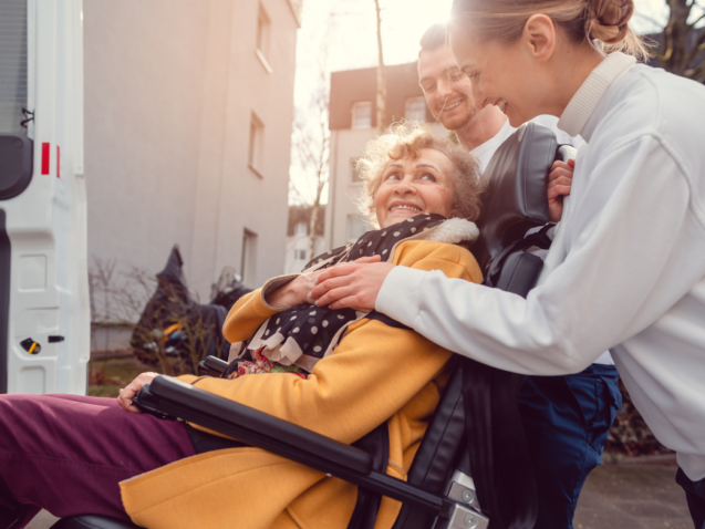 seniorka na wózku jest wprowadzana do samochodu