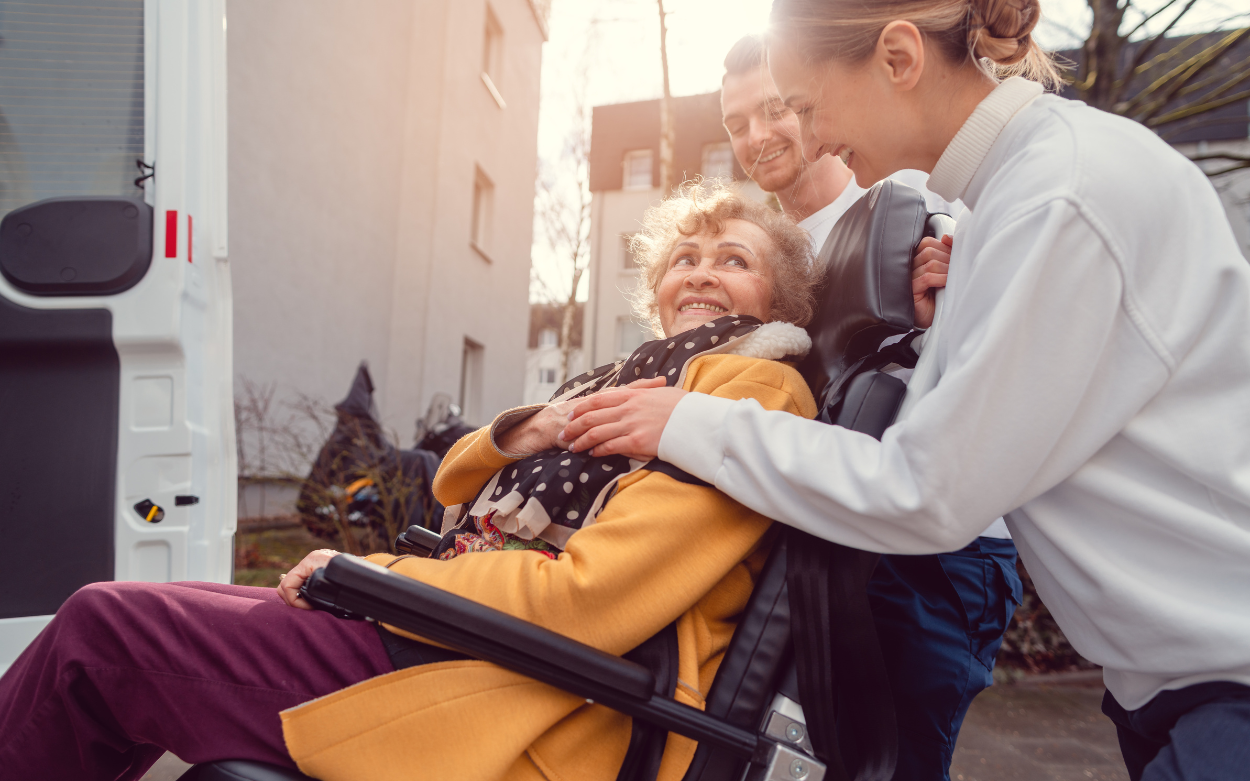 seniorka na wózku jest wprowadzana do samochodu